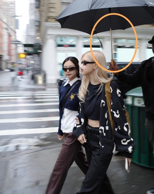Blackpink Rosé and Jennie accompanied by bodyguards holding umbrellas on the streets of New York...